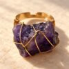 Bague roche améthyste Intuition en améthyste brute sertie de fil doré, vue de face sur marbre