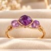 Bague mini Intuition, trois perles d'améthyste facettées sur fil doré, sur velours