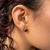 01-boucles-oreilles-mellia-oeil-de-tigre Puce d’oreille MELLIA en œil de tigre portée, gros plan sur l’oreille, reflets miel et brun