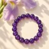 Bracelet en perles rondes d'améthyste 8 mm posé près d'une fleur d'iris