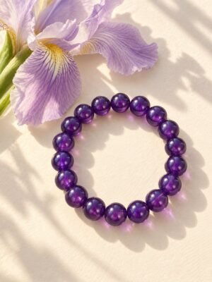 01-bracelet-perles-amethyste-8mm Bracelet en perles rondes d'améthyste 8 mm posé près d'une fleur d'iris