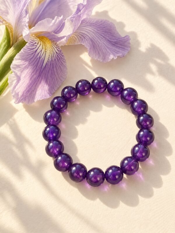 Bracelet en perles rondes d'améthyste 8 mm posé près d'une fleur d'iris