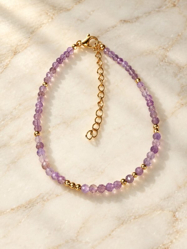 01-bracelet-perles-lilas-amethyste Bracelet en fines perles d'améthyste lilas facettées et perles dorées posé sur du marbre