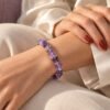 Bracelet élastique éclats d'améthyste porté au poignet, sur satin