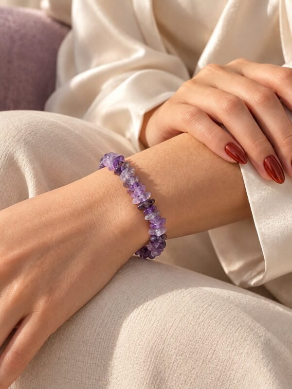 Bracelet élastique éclats d'améthyste porté au poignet, sur satin