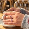 Bague mini Intuition en améthyste portée en terrasse, tasse de café à la main