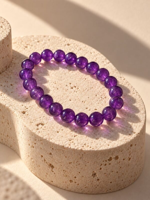 Bracelet perles d'améthyste 8 mm posé sur une pierre beige