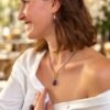 Femme souriante portant le collier améthyste goutte en terrasse