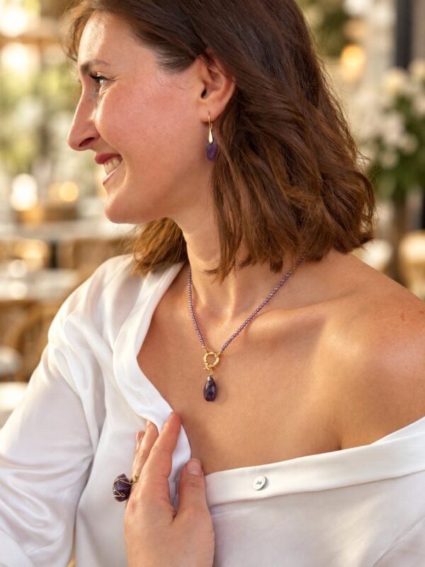 Femme souriante portant le collier améthyste goutte en terrasse