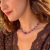 Collier perles améthyste INTUITION porté sur une tenue en dentelle marron, pierre centrale facettée visible