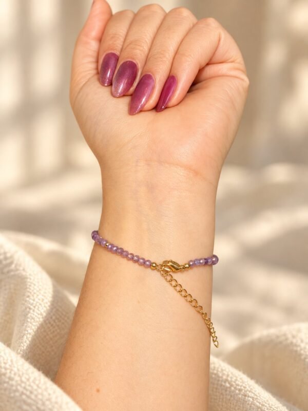 06-bracelet-perles-lilas-amethyste Bracelet améthyste lilas porté au poignet sur un pull crème