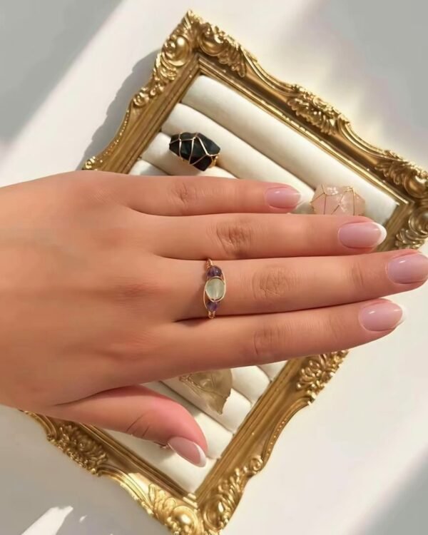 Main portant la bague mini Intuition x Lina sur un cadre doré
