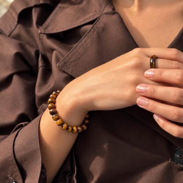 Bracelet MELLIA œil de tigre en gros plan sur le poignet, mains sur une chemise marron