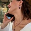 Collier améthyste goutte porté au téléphone en terrasse parisienne