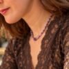 Collier perles améthyste porté de profil sur dentelle marron, bas du visage visible