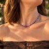 Collier perles améthyste INTUITION porté en extérieur, pierre centrale facettée et lumière naturelle