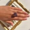 Bague roche améthyste Intuition en améthyste portée sur la main, cadre doré
