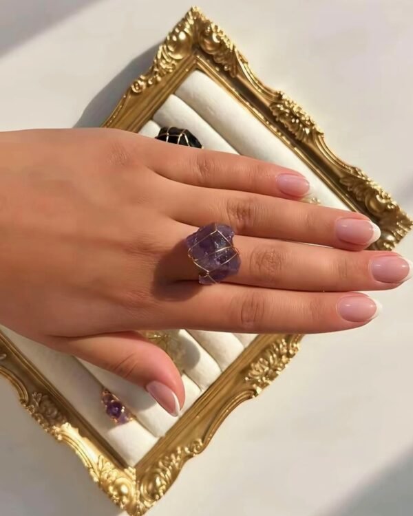 Bague roche améthyste Intuition en améthyste portée sur la main, cadre doré