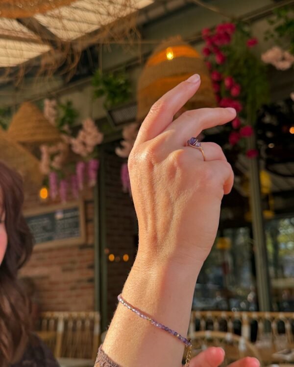 10-bracelet-perles-lilas-amethyste Main portant le bracelet améthyste lilas en terrasse fleurie