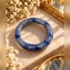 Bague AZUR en sodalite naturelle bleue posée sur un socle en marbre avec gypsophile