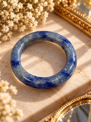 Bague AZUR – sodalite 1 Bague AZUR en sodalite naturelle bleue posée sur un socle en marbre avec gypsophile