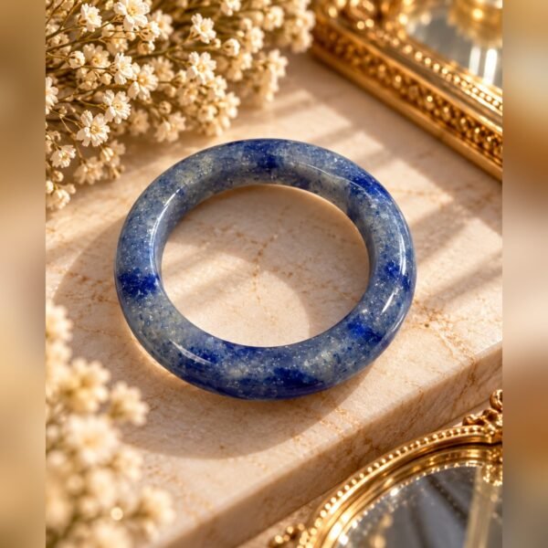 Bague AZUR en sodalite naturelle bleue posée sur un socle en marbre avec gypsophile