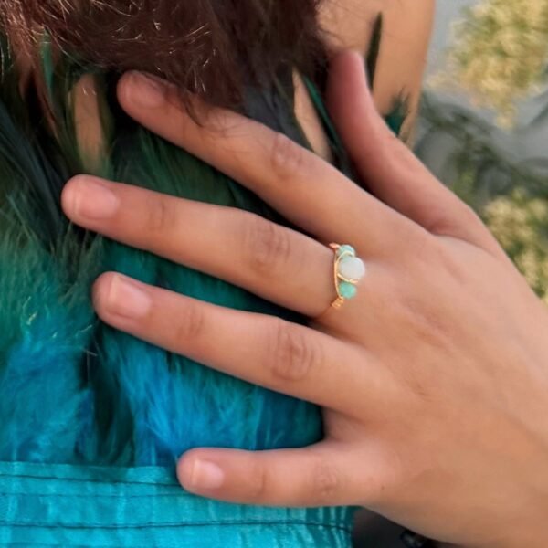 Bague AZURA – amazonite 4 Bague AZURA amazonite portée, main posée sur des plumes turquoise
