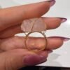 Bague brute en quartz rose naturel enlacée de fil, finition ton or, tenue entre les doigts – vue 3