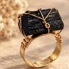 Bague brute en tourmaline noire naturelle enlacée de fil, finition ton or, posée sur pierre claire – vue 2