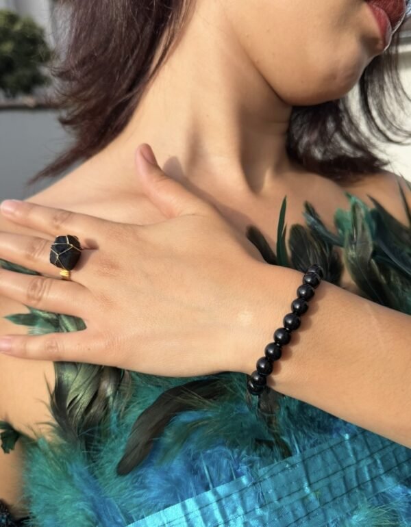 Bague brute en tourmaline noire naturelle enlacée de fil, finition ton or, portée à la main – vue 4