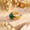 Bague MALYA en malachite posée sur une pierre claire avec gypsophile