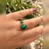 Bague MALYA en malachite portée à la main avec feuillage