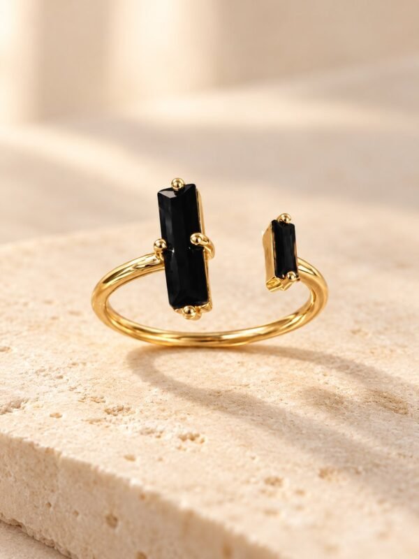 Bague NÉRA asymétrique en obsidienne noire et cuivre couleur dorée, de face sur pierre beige – vue 2