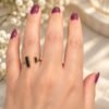 Bague NÉRA en obsidienne noire portée au doigt, fleurs de gypsophile en arrière-plan – vue 3