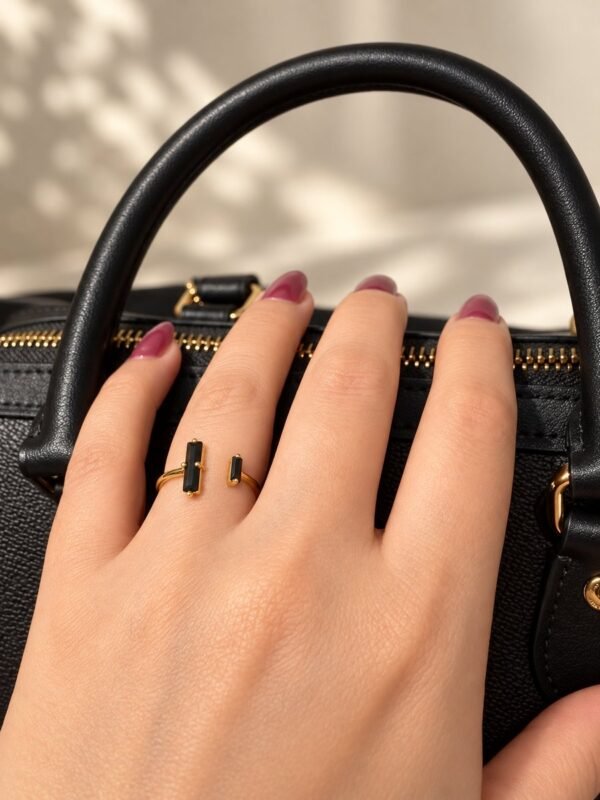 Bague NÉRA en obsidienne noire portée, main posée sur un sac en cuir noir – vue 4