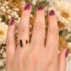 Bague NÉRA en obsidienne noire portée au doigt, fleurs séchées en arrière-plan – vue 5