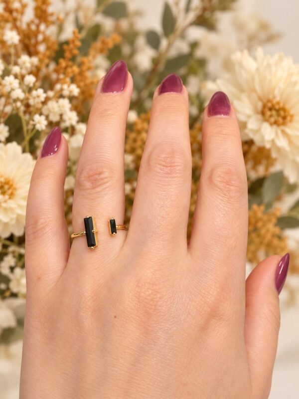 Bague NÉRA en obsidienne noire portée au doigt, fleurs séchées en arrière-plan – vue 5