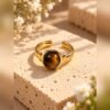 Bague SOLÉNA œil de tigre 1 Bague SOLÉNA en œil de tigre, cabochon rond sur monture ouverte aux finitions dorées – Serinaé