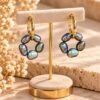 Boucles d’oreilles ÉPURE Noires, cercles de cinq perles d’eau douce noires sur créoles finition ton or, présentées sur un support – vue 1