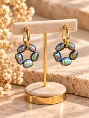 boucles-epure-noires-perles-eau-douce-1 Boucles d’oreilles ÉPURE Noires, cercles de cinq perles d’eau douce noires sur créoles finition ton or, présentées sur un support – vue 1