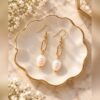 Boucles d’oreilles ÉPURE – Perle 1 Boucles d’oreilles ÉPURE, maillon ovale et perle aux reflets nacrés, sur coupelle festonnée – Serinaé