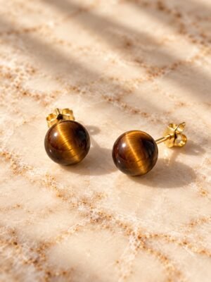 Boucles d’oreilles puces œil de tigre MELLIA Boucles d’oreilles puces MELLIA en œil de tigre naturel à bouchon, posées sur marbre clair – vue 1