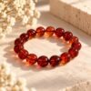 Bracelet AMBRINE en perles ambrées rondes de 10 mm aux reflets cognac et miel, posé sur pierre claire – Serinaé