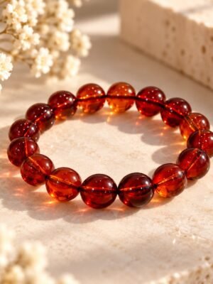 Bracelet AMBRINE en perles ambrées rondes de 10 mm aux reflets cognac et miel, posé sur pierre claire – Serinaé