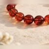Gros plan sur les perles ambrées de 10 mm du bracelet AMBRINE, nuances rouge cognac – Serinaé