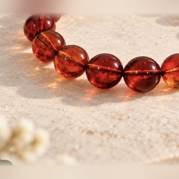 Gros plan sur les perles ambrées de 10 mm du bracelet AMBRINE, nuances rouge cognac – Serinaé