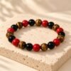 Bracelet FORCE & ÉNERGIE – obsidienne, agate rouge et œil de tigre 1 Bracelet FORCE & ÉNERGIE SERINAÉ en perles d’obsidienne noire, d’agate rouge et d’œil de tigre, posé sur une pierre claire