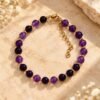 Bracelet INTUITION Nuances en perles rondes d'améthyste violet clair et violet profond, petites perles intercalaires, posé sur une pierre
