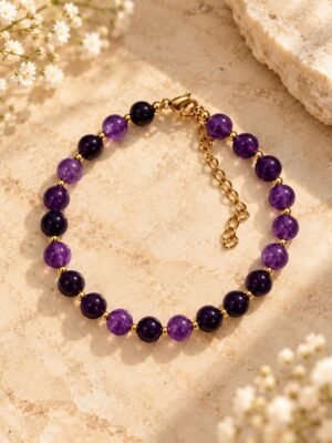 Bracelet INTUITION Nuances – perles d'améthyste 1 Bracelet INTUITION Nuances en perles rondes d'améthyste violet clair et violet profond, petites perles intercalaires, posé sur une pierre