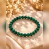 bracelet-malya-malachite-8mm Bracelet MALYA en malachite naturelle à perles de 8 mm posé sur un bloc de pierre